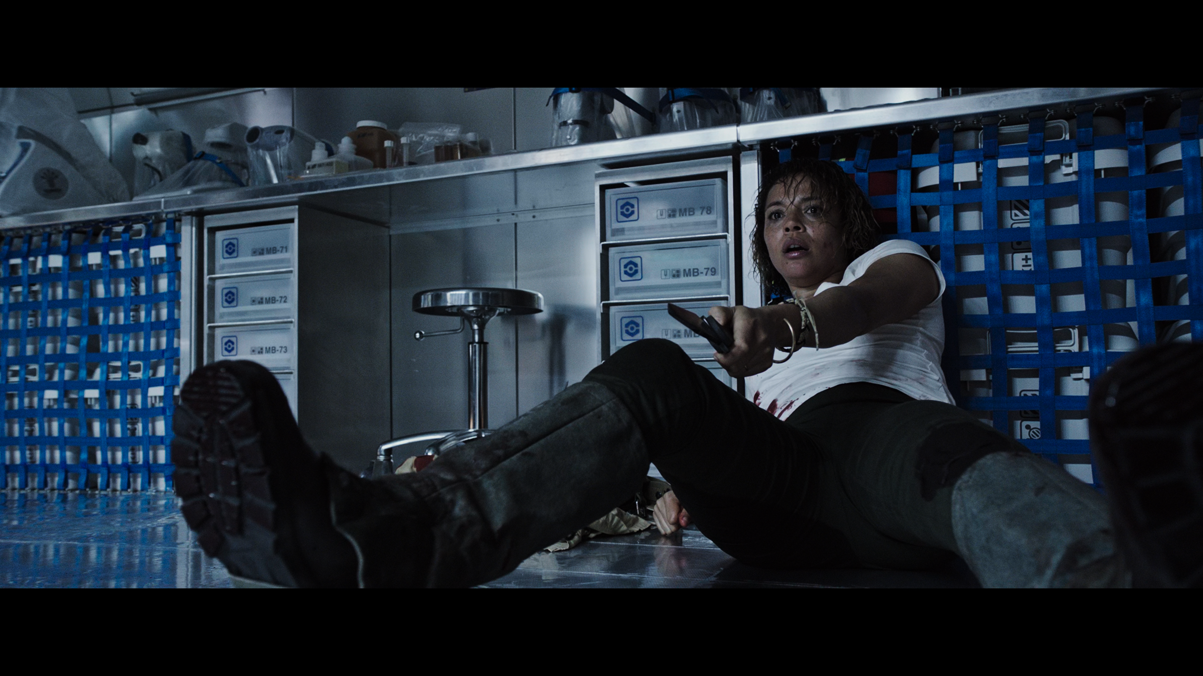 A bloodied crew member sprawls across the medbay floor in terror