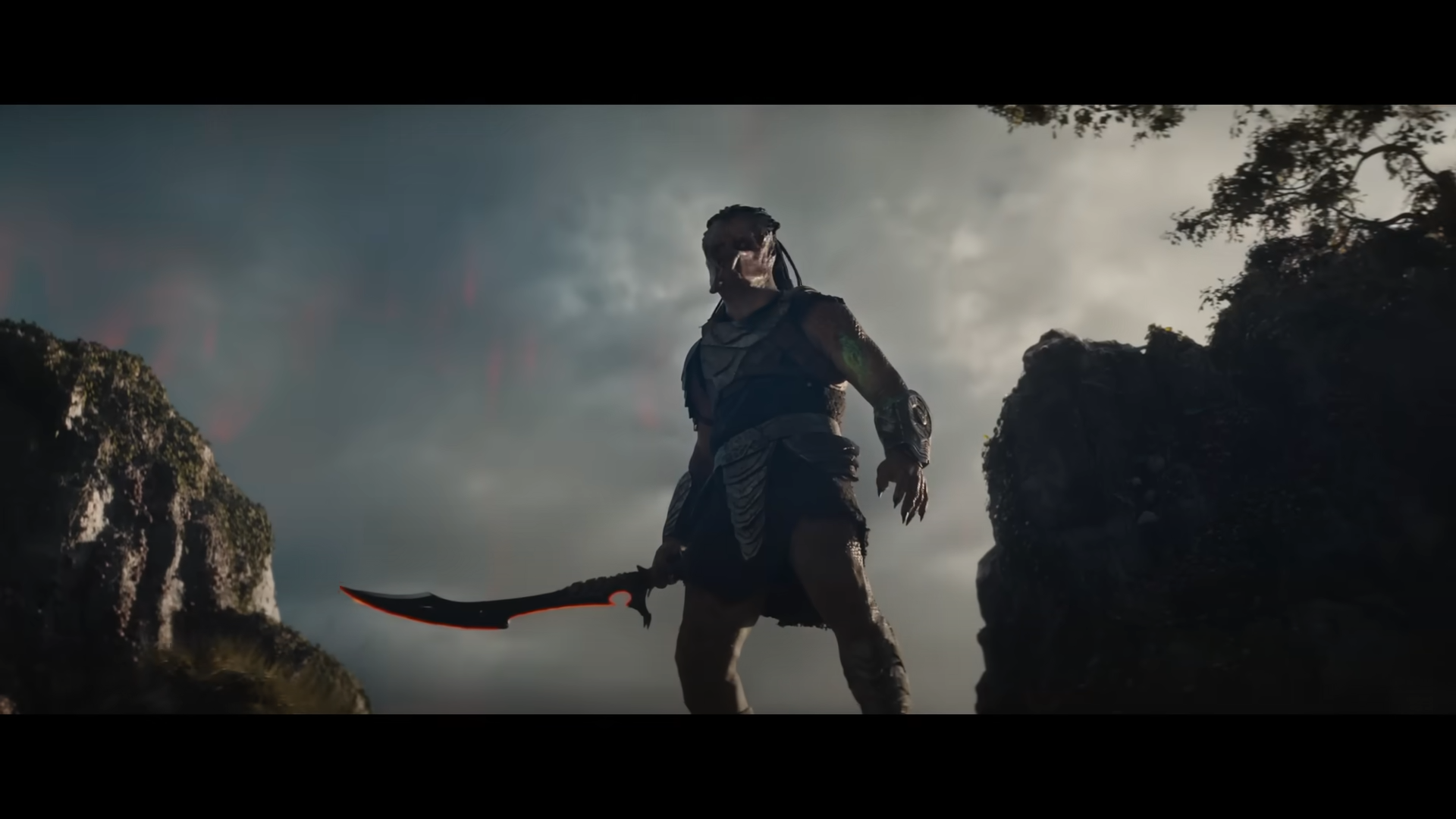 Predator stands atop a rocky pass, brandishing a glowing curved blade