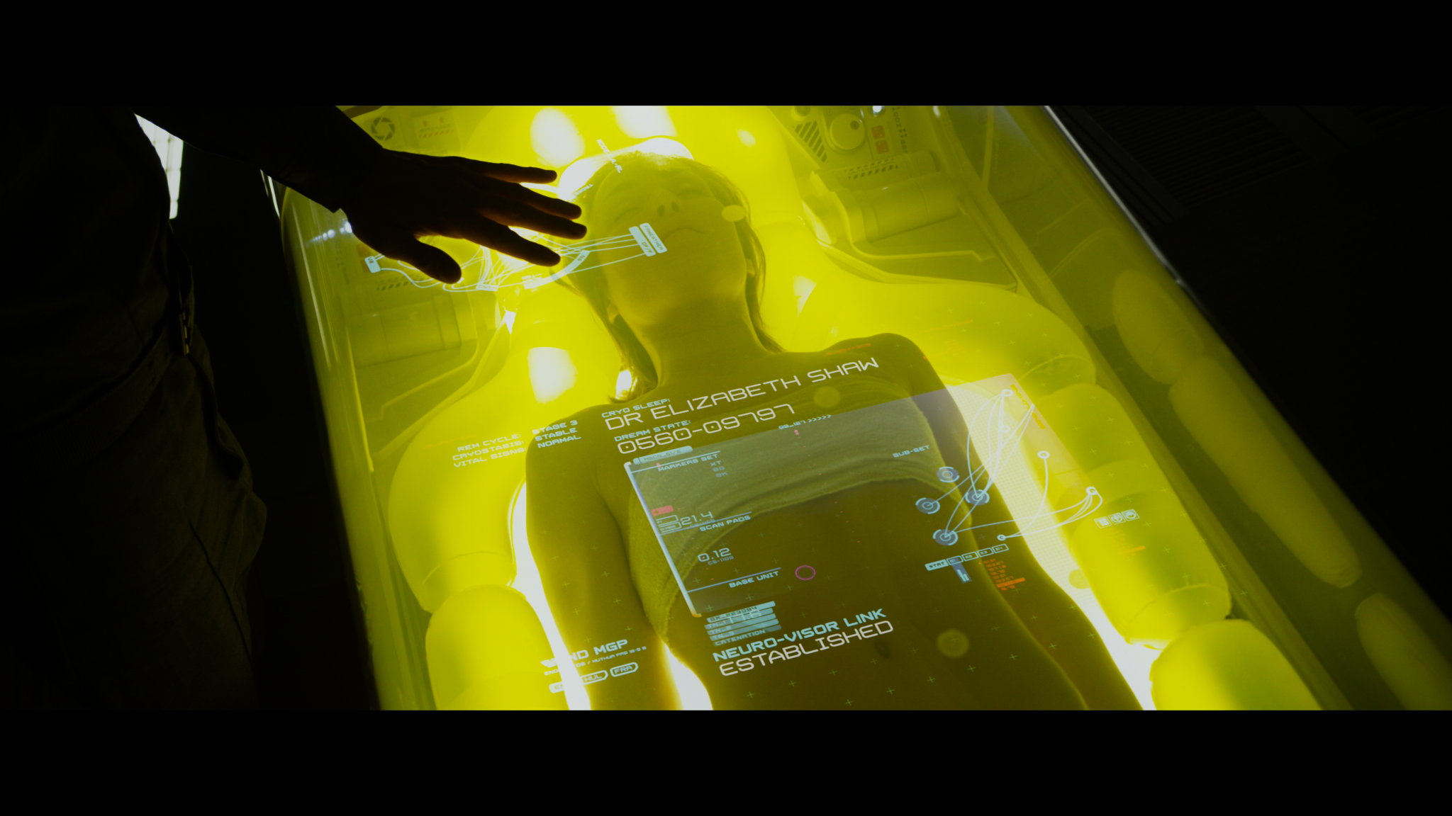 Dr. Elizabeth Shaw under yellow glass—vitals and holographic UI in the cryo/med pod